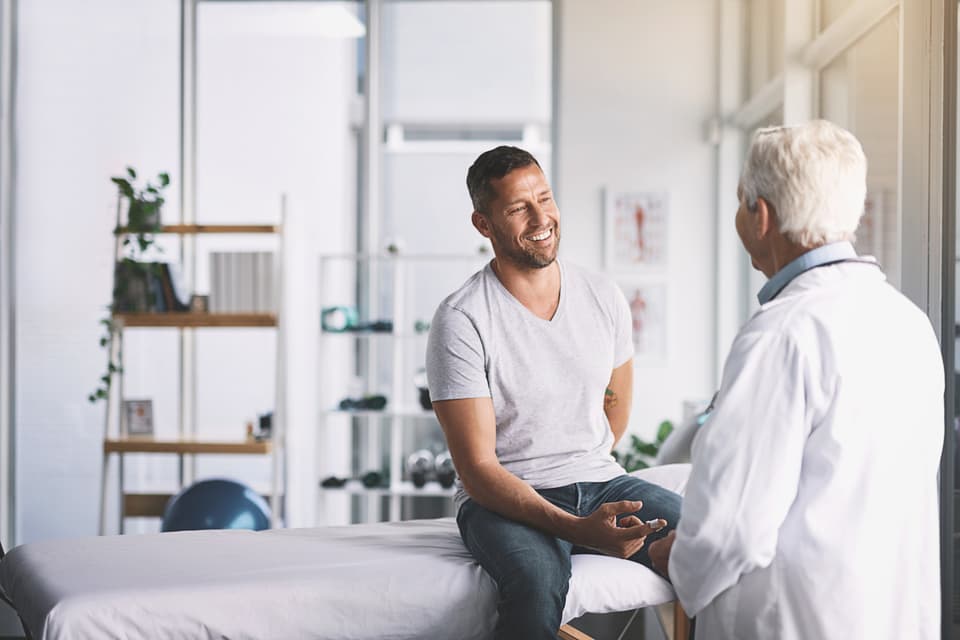 Un hombre hablando con su médico durante una consulta de atención hormonal