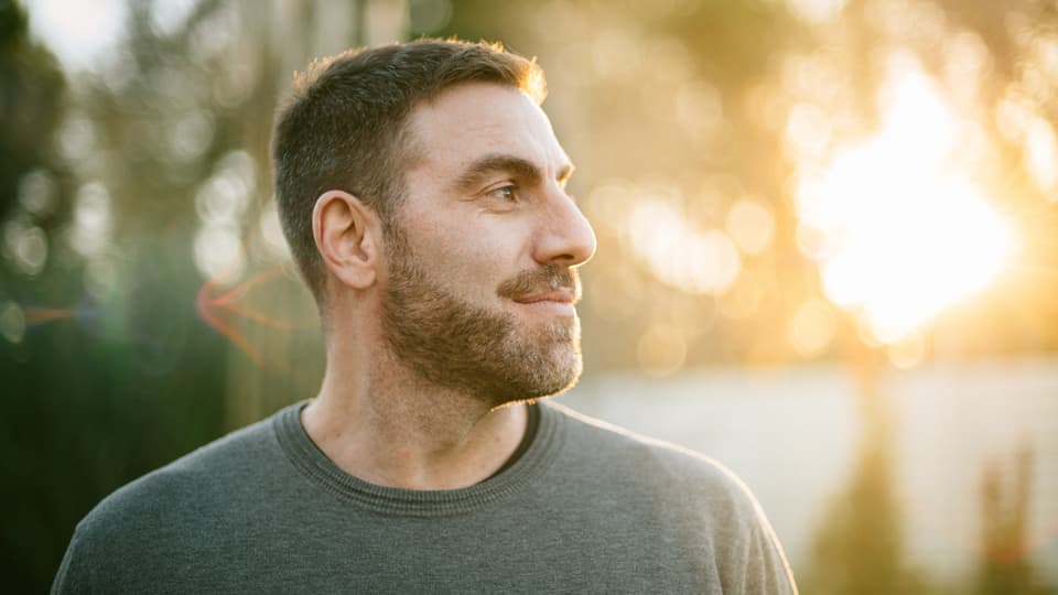 Un hombre al aire libre al atardecer, mirando a lo lejos