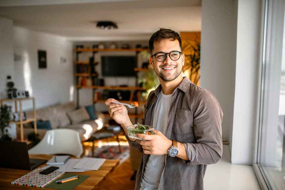 Un hombre comiendo una ensalada en casa