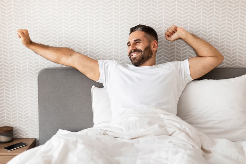 Un hombre estirándose al despertar en la mañana